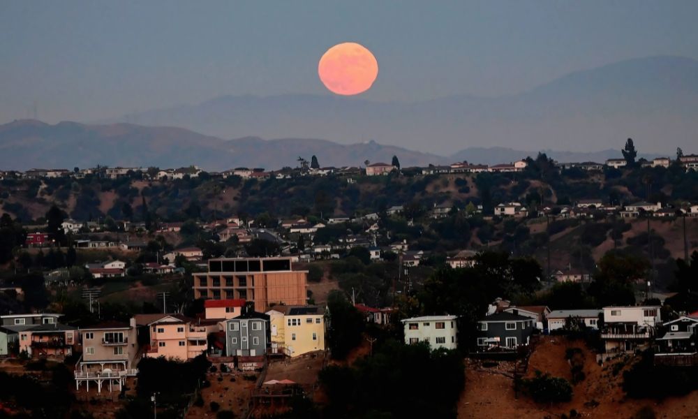 Orange moon near the horizon appearing larger due to atmospheric scattering and optical illusion