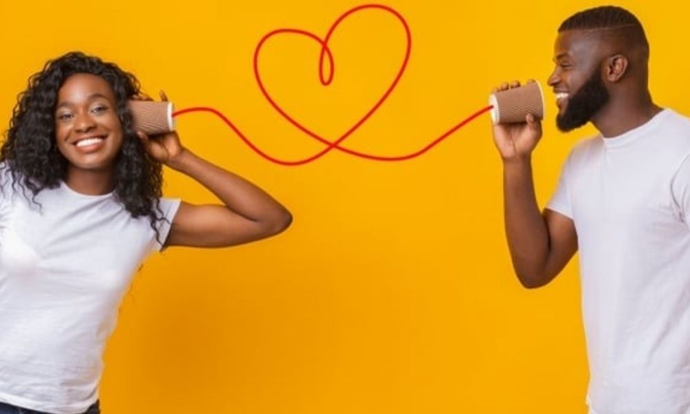 Happy couple using tin can telephones with heart-shaped string symbolizing better communication in a healthy relationship
